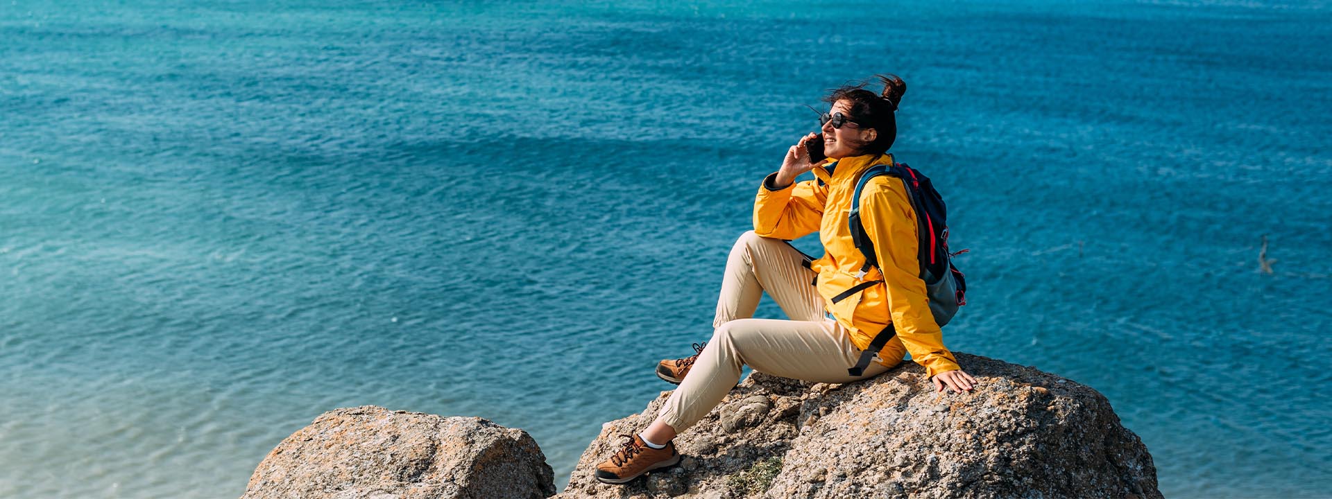 A woman sitting on the rock near the sea