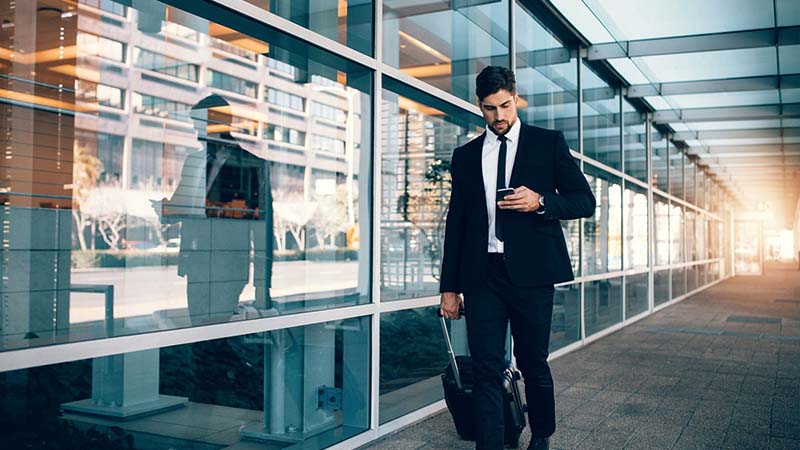 a person in a suit walking with his luggage